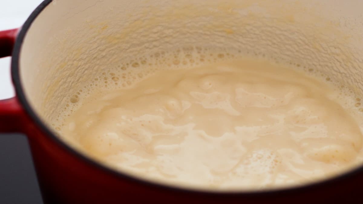 Simmering, reduced, and slightly thickened milk and sugar mixture in a pot