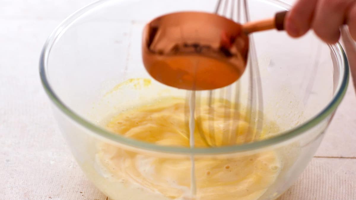 Tempering the egg yolks mixture with hot milk while whisking
