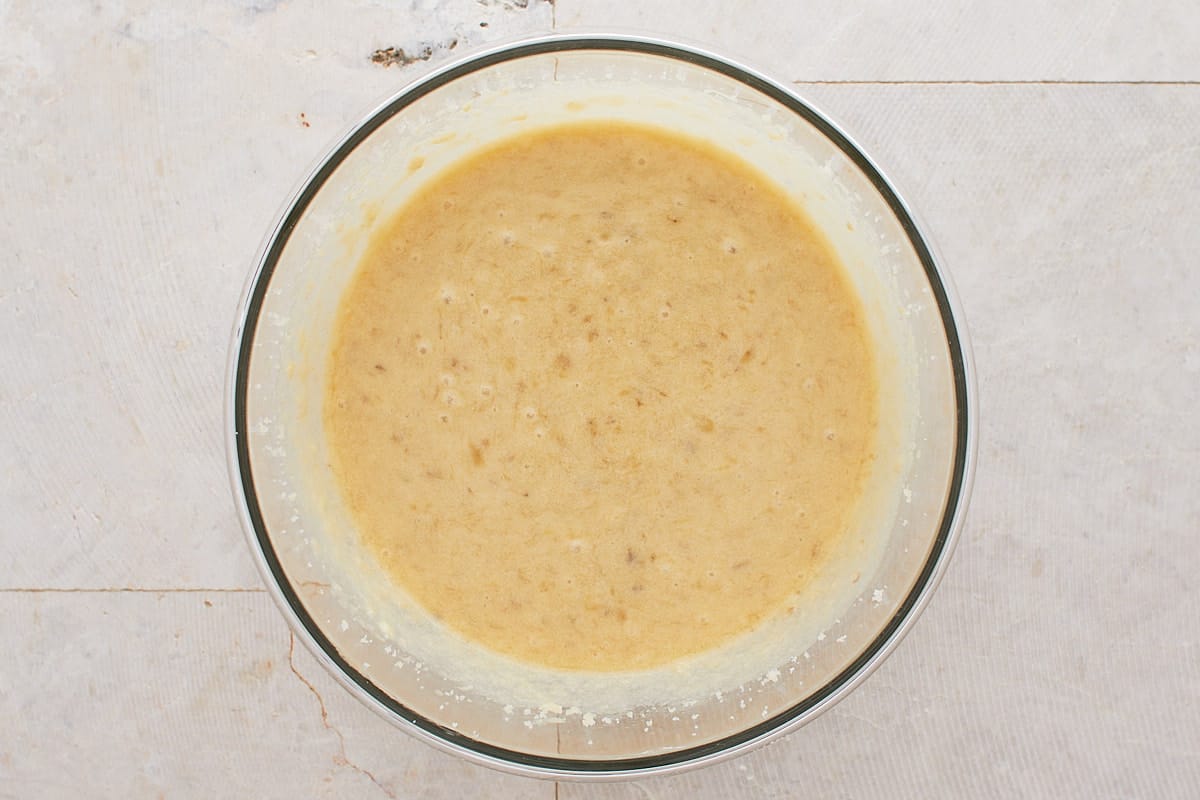 Butter, sugar, eggs, mashed bananas, oil, and vanilla mixed in a mixing bowl