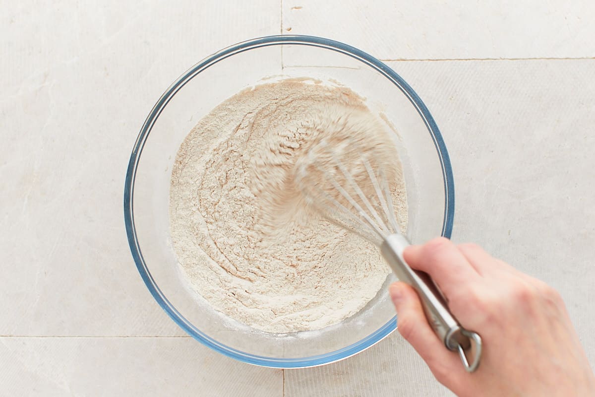 Whisking flour, baking powder, salt, and pumpkin spices in a mixing bowl