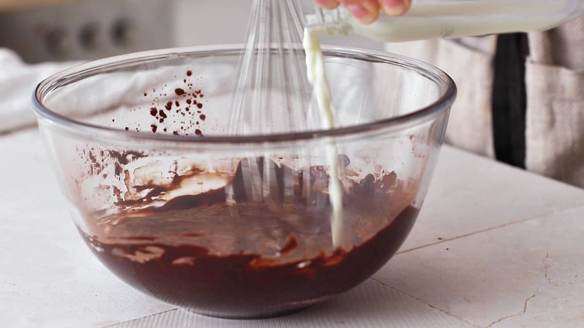 Pouring hot milk into the chocolate frosting