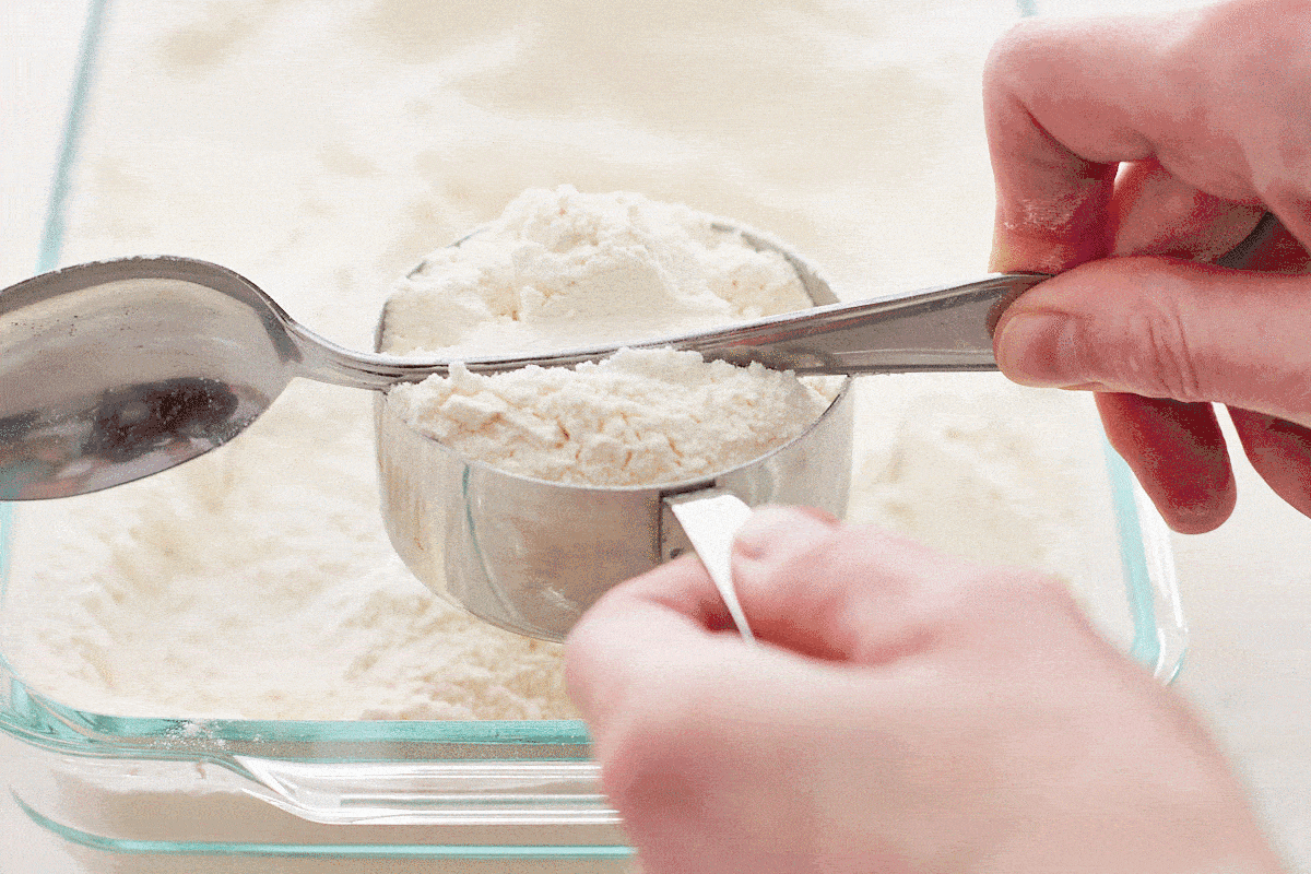 Animated gif showing how to level flour with the handle of a spoon
