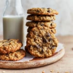 Stack of oatmeal raisin chocolate chip cookies next to glass of milk