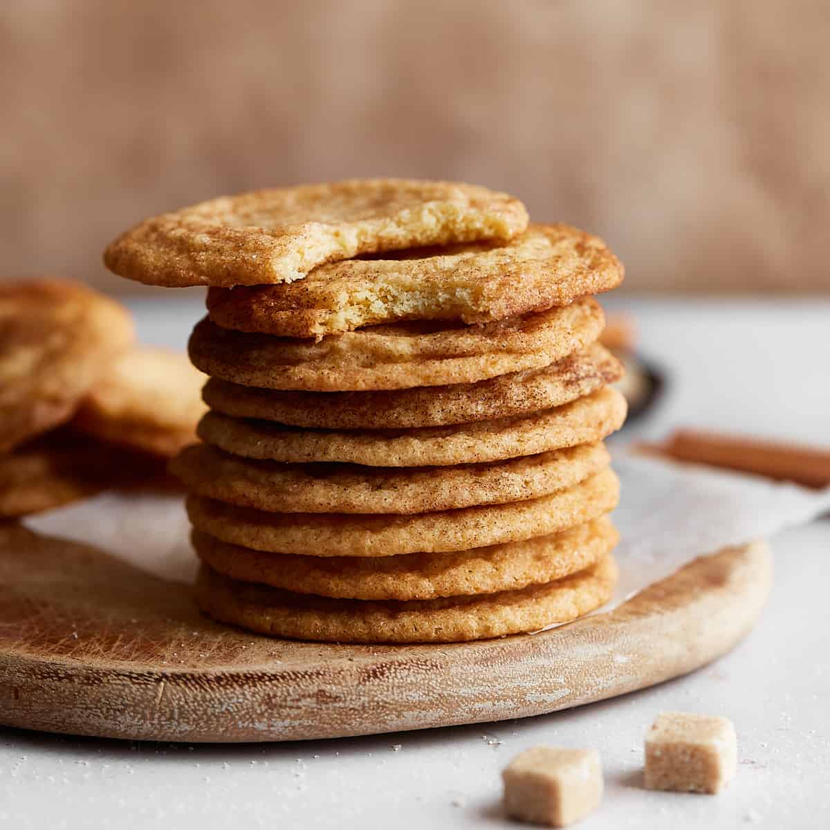 A stack of cookies on a wooden board with sugar and cinnamon decoration around it