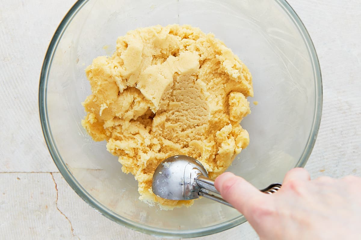 Scooping cookie dough out of a mixing bowl