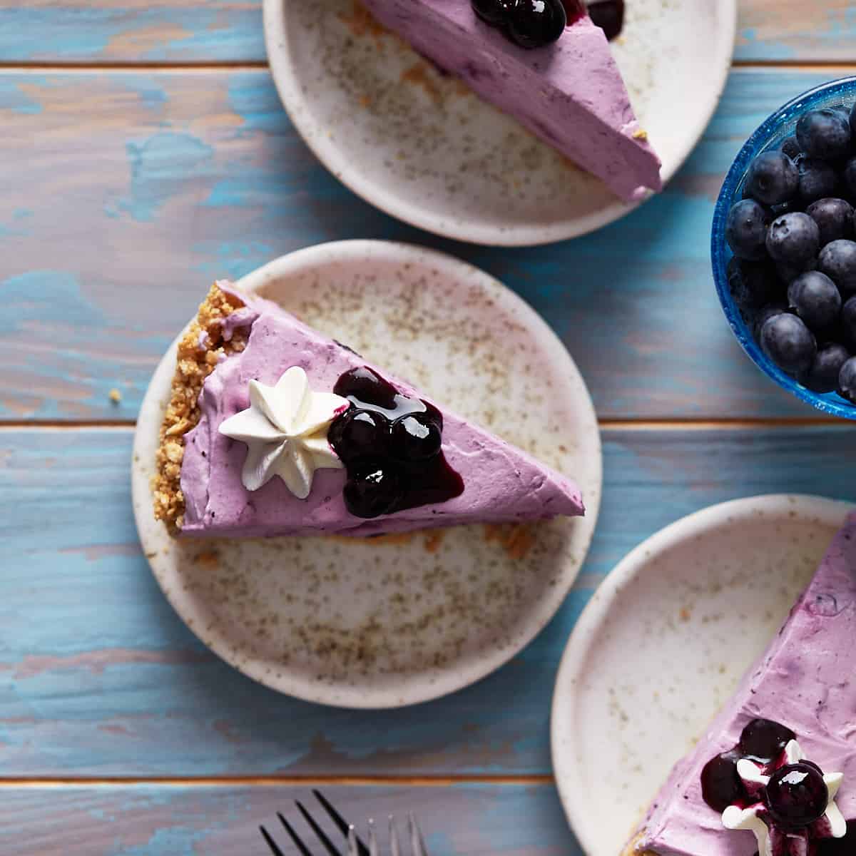 Slices of no-bake blueberry cheesecake plated on dessert plates.