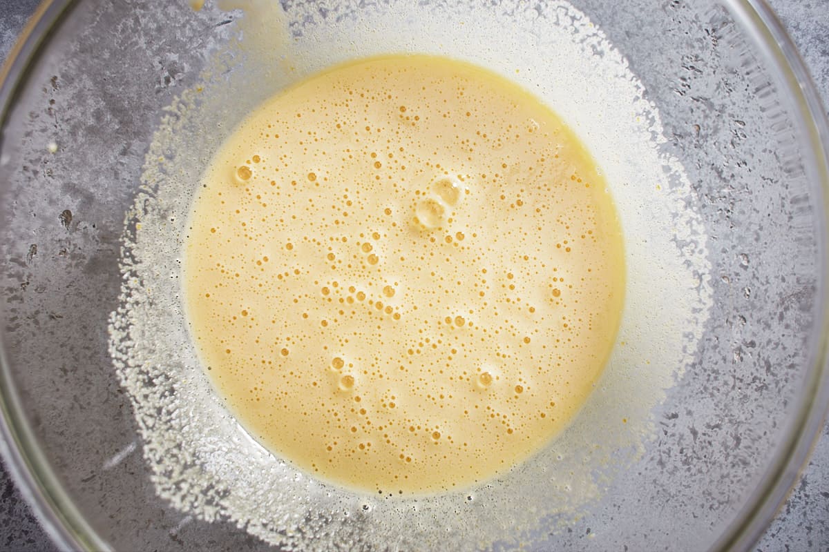 Eggs, sugar, and vanilla whisked with bubbles forming on the surface