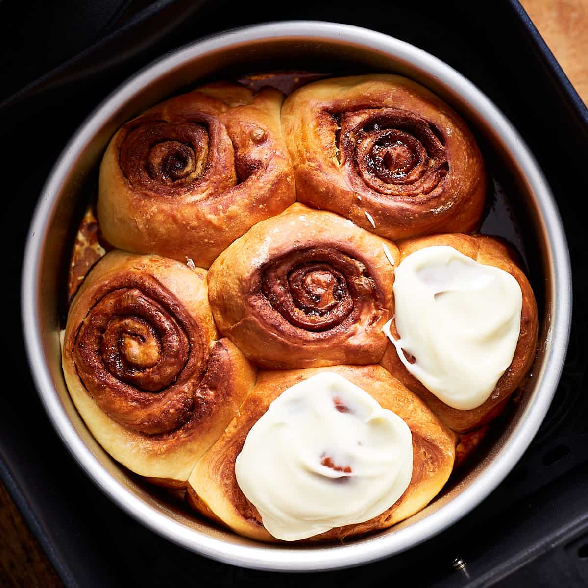Baked rolls, two of them glazed, in an air fryer basket