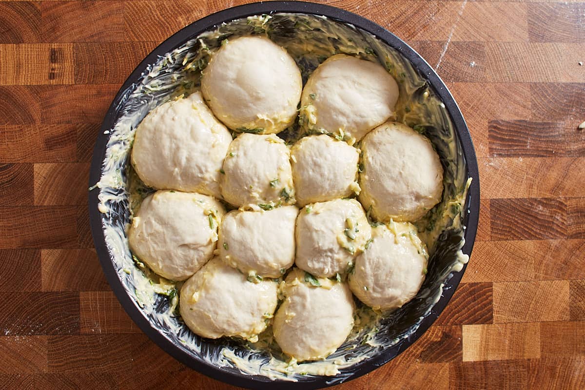 Pizza dough balls brushed with butter in a pan