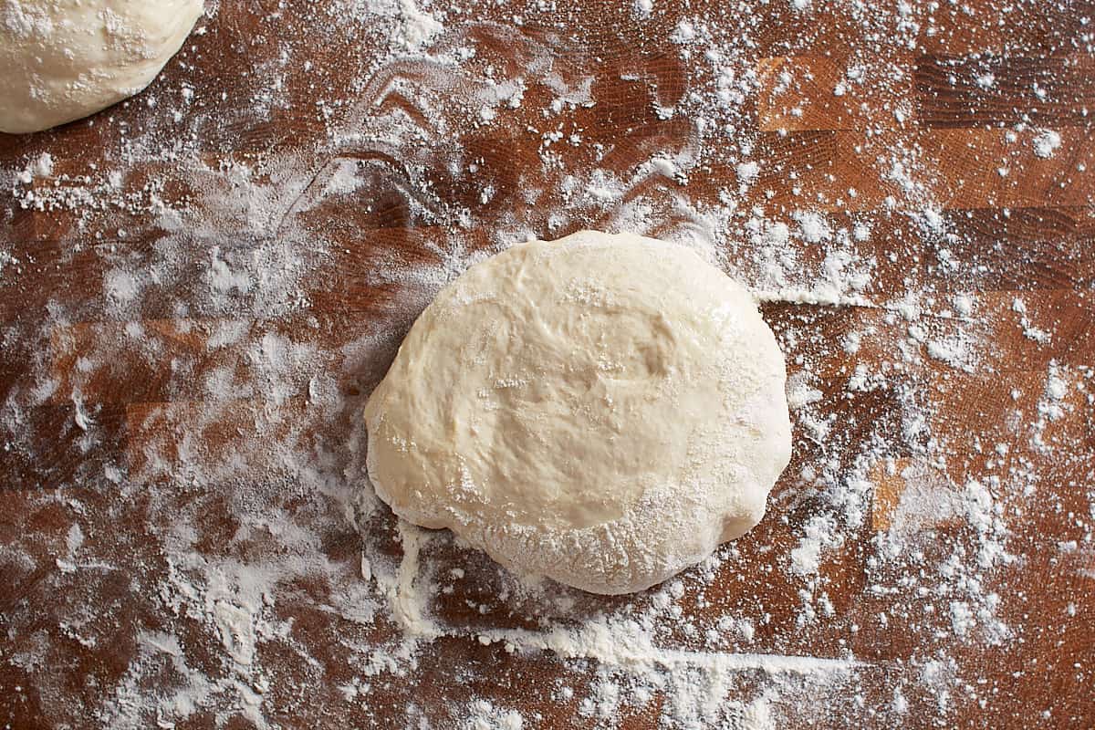 Flour dusted pizza dough on work surface