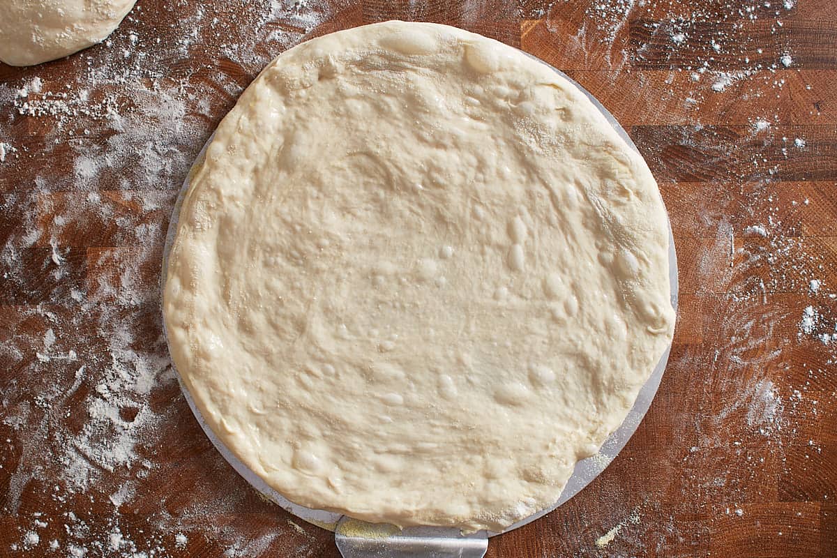 Stretched and shaped pizza dough on a pizza peel