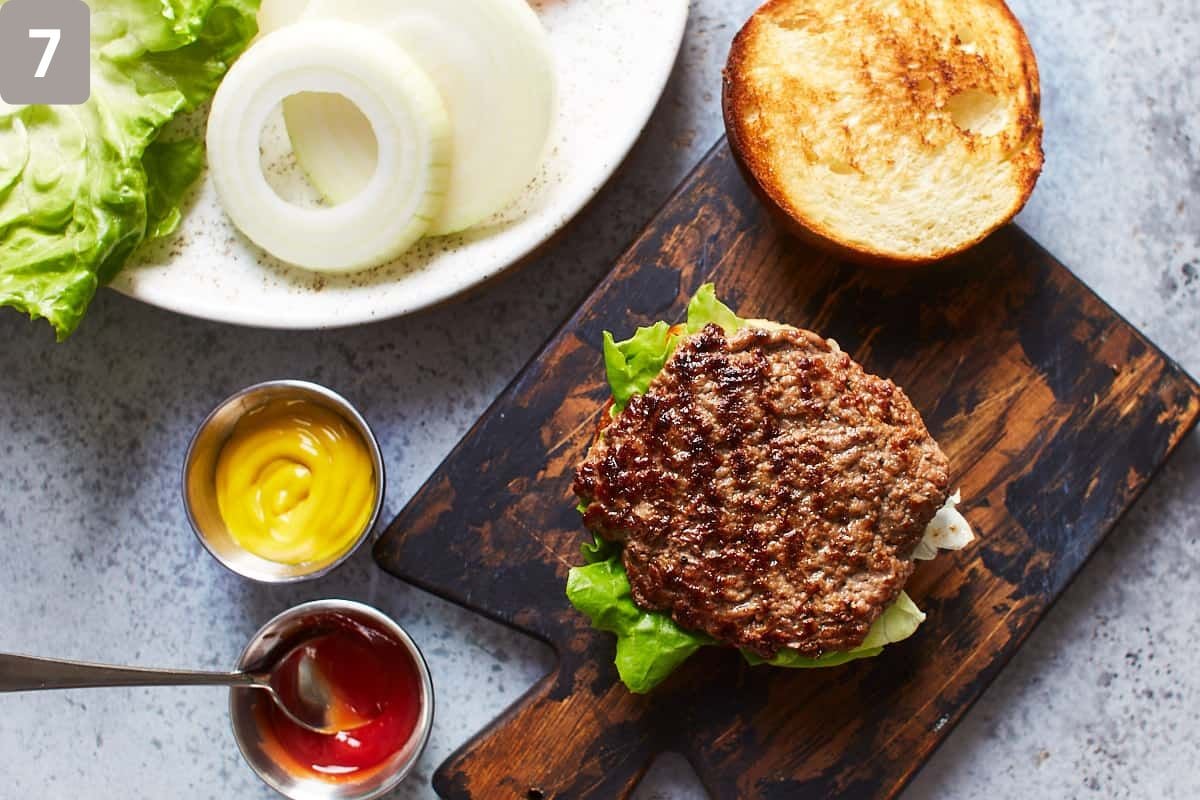 Burger patty on bun and additional toppings surrounding the burger