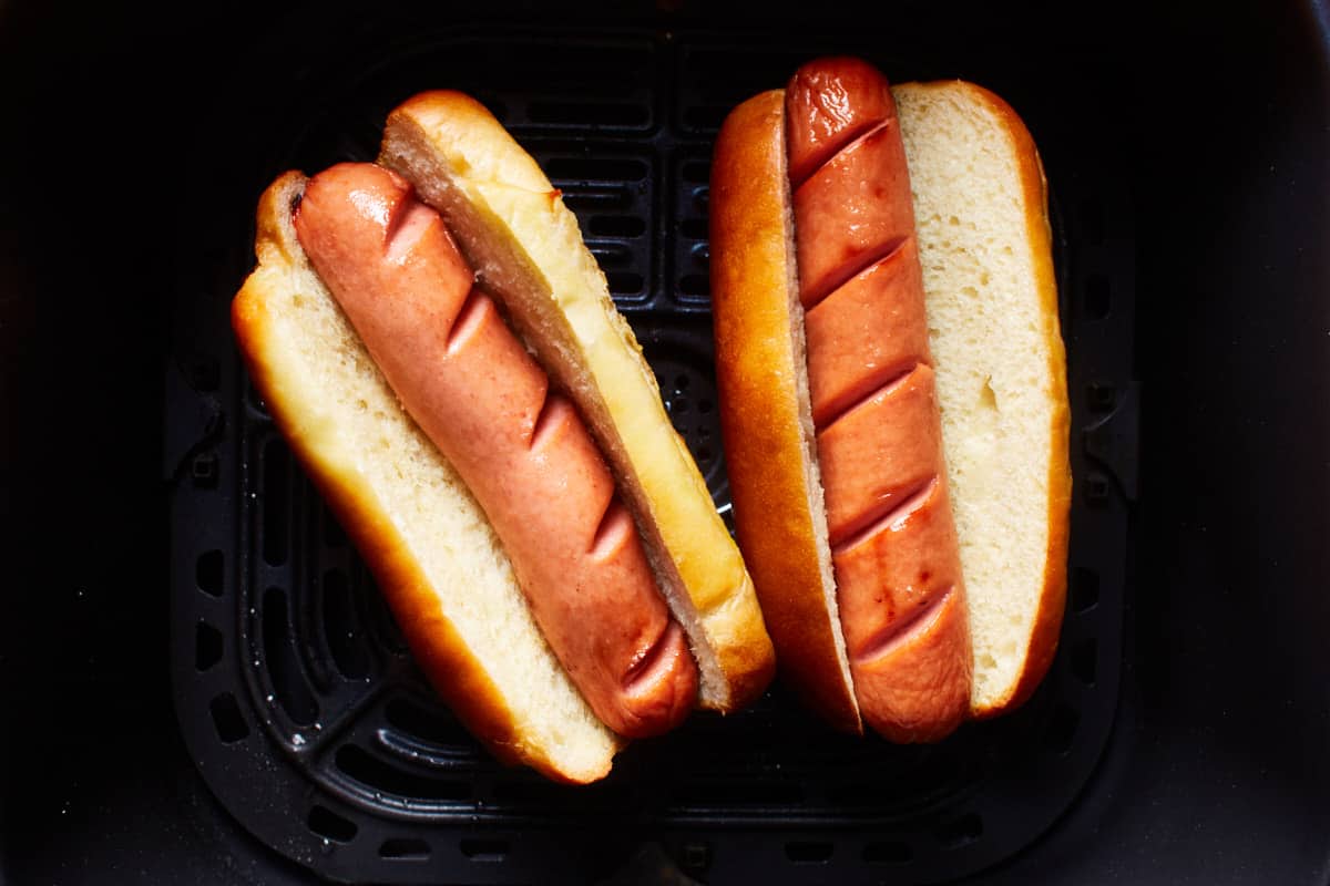 Cooked frankfurters placed in a bun in an air fryer basket