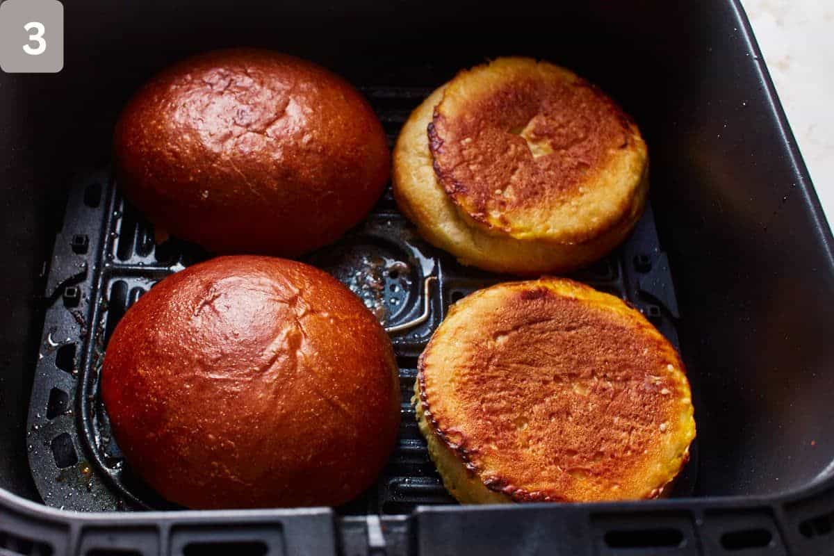 Burger buns in an air fryer basket.