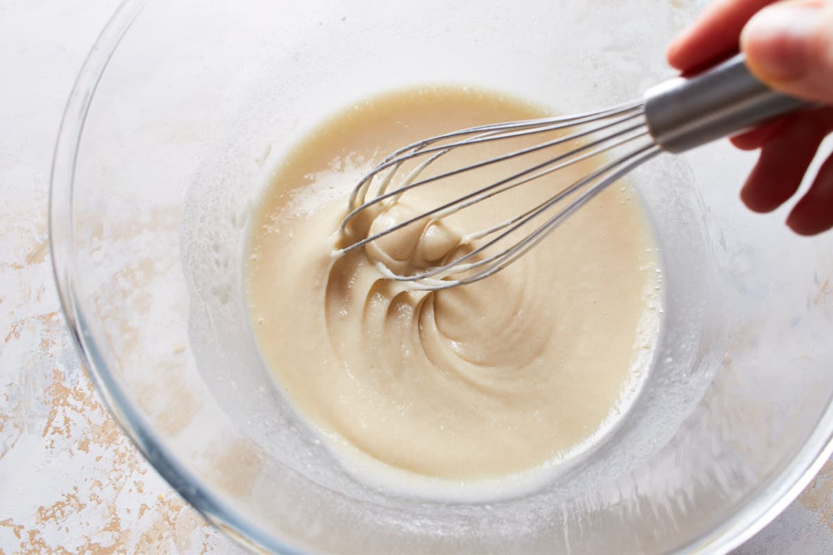 Whisking flour, baking powder, salt, sugar, and milk in a bowl