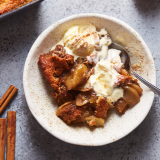 A bowl of freshly baked apple cobbler with ice cream melting on top