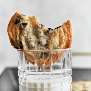 Half eaten cookie placed on upright on a glass of milk