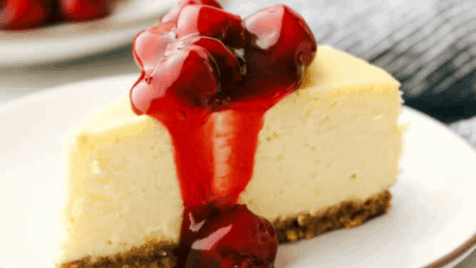 a cherry sauce topped cheesecake slice on a white plate