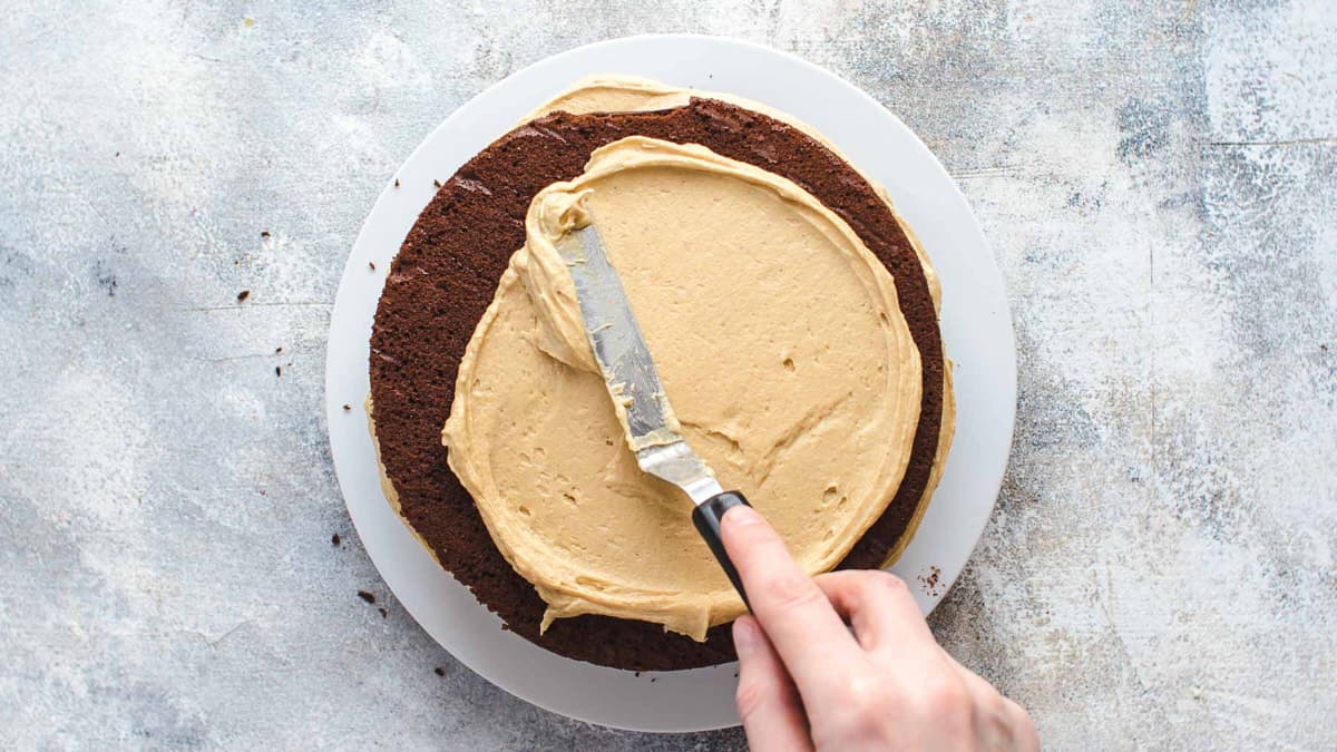 Spreading peanut butter frosting over chocolate cake