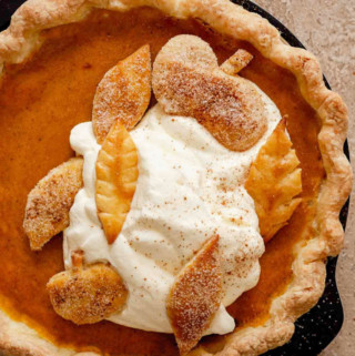 Baked pumpkin pie with whipped topping and pie crust decoration