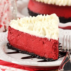 a slice of red velvet cheesecake topped with whipped topping