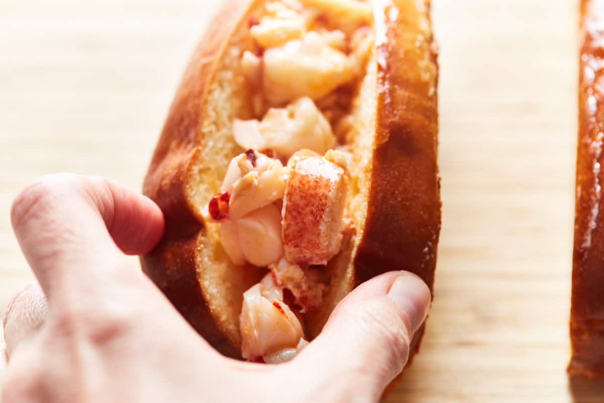 Filling cooked lobster meat in a hot dog bun