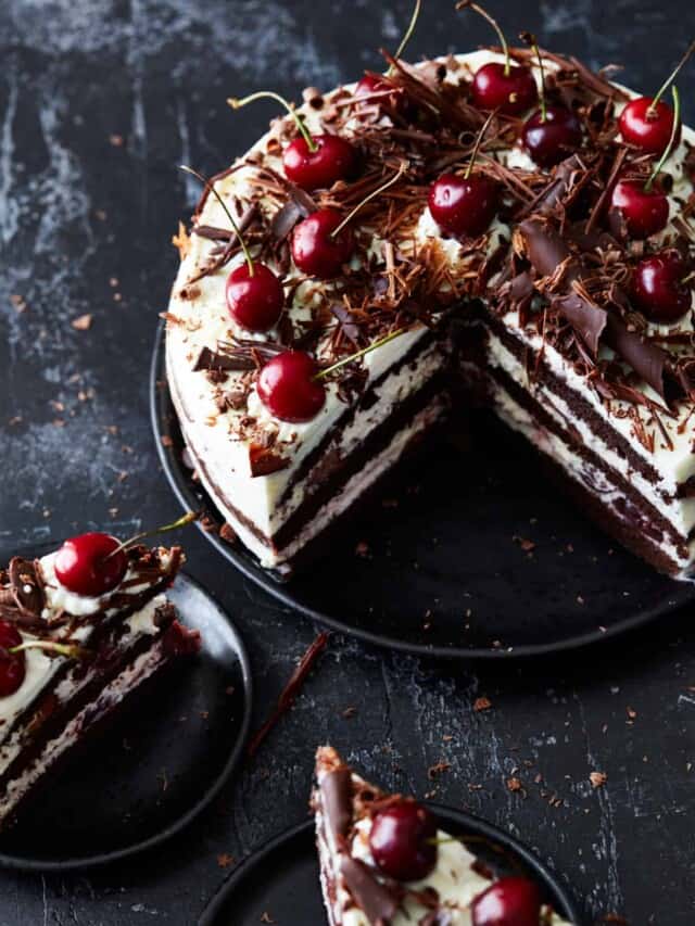Baked and decorated Black Forest cake on a cake plate with a quarter of it missing