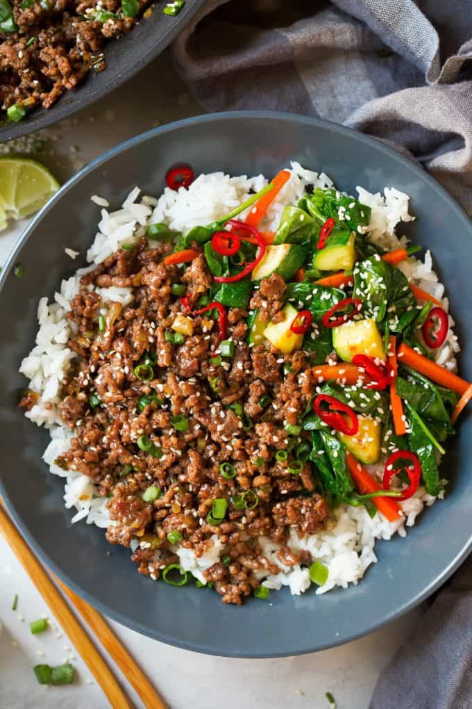 A bowl of rice topped with beef and vegetables
