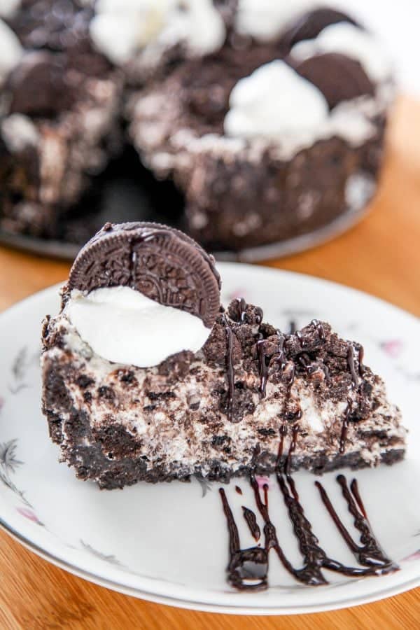 a slice of a no bake cheesecake topped with whipped cream and an oreo cookie on a white plate