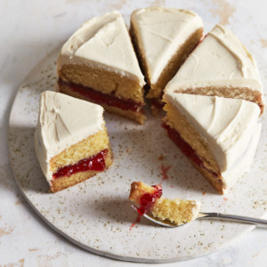 Five slices of vanilla cake filled with strawberry jam and buttercream on a white cake plate