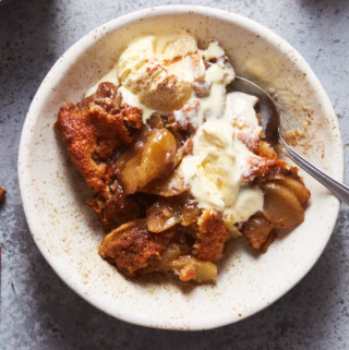 A bowl of freshly baked apple cobbler with ice cream melting on top