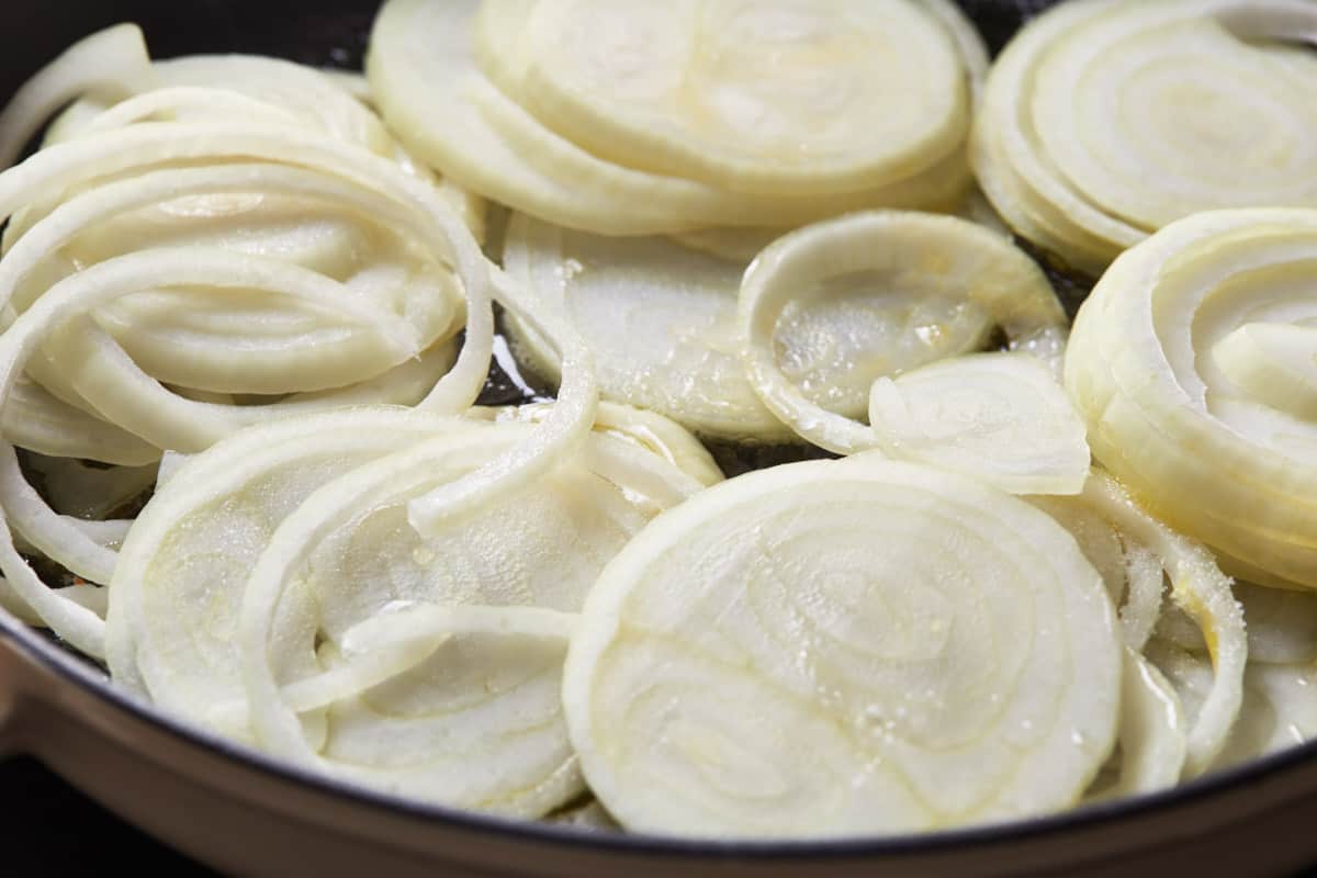 Uncooked onion slices in a cast iron pan