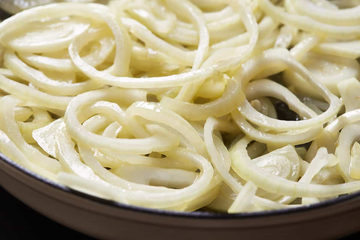 Lightly softened onion slices cooking in a pan