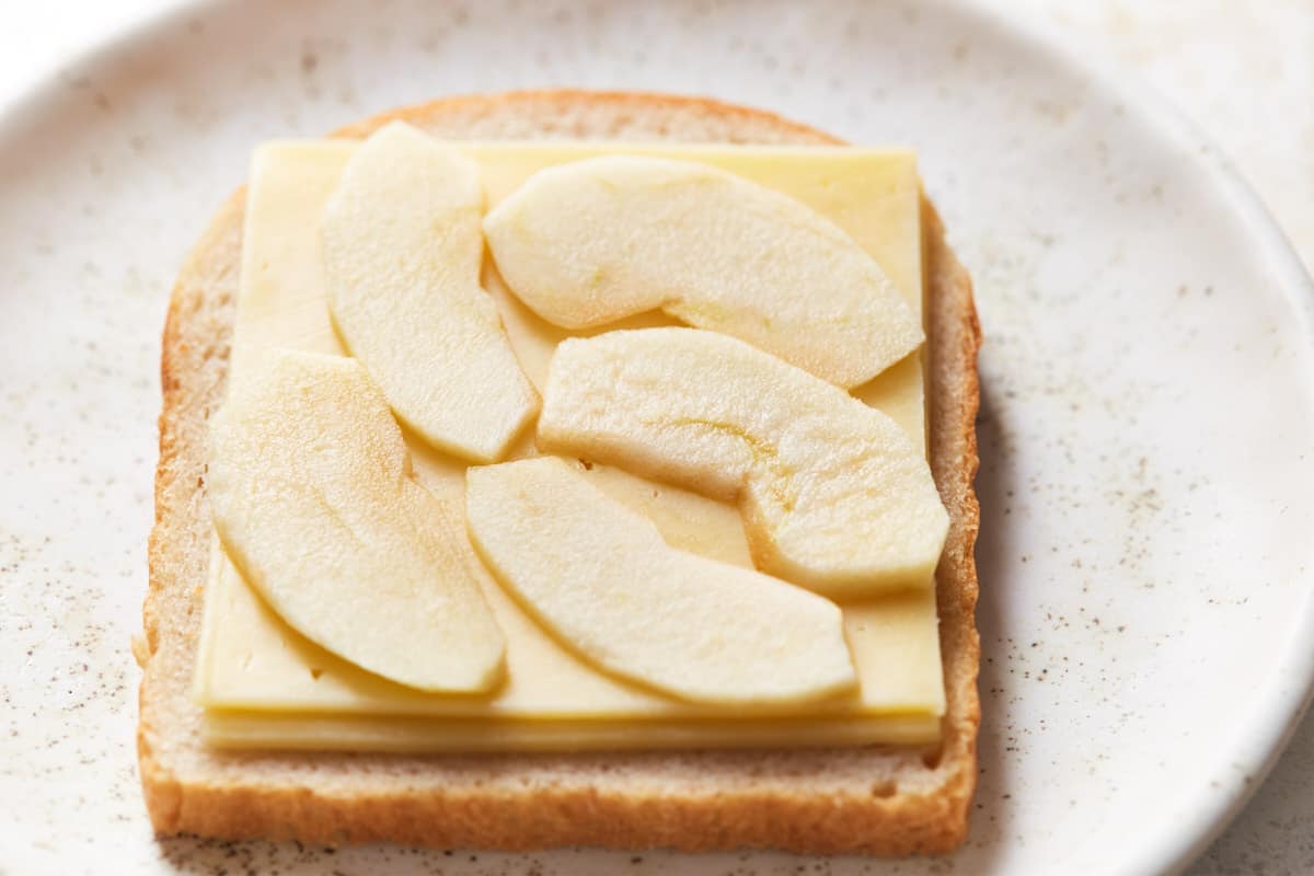 A slice of bread topped with cheddar and apple
