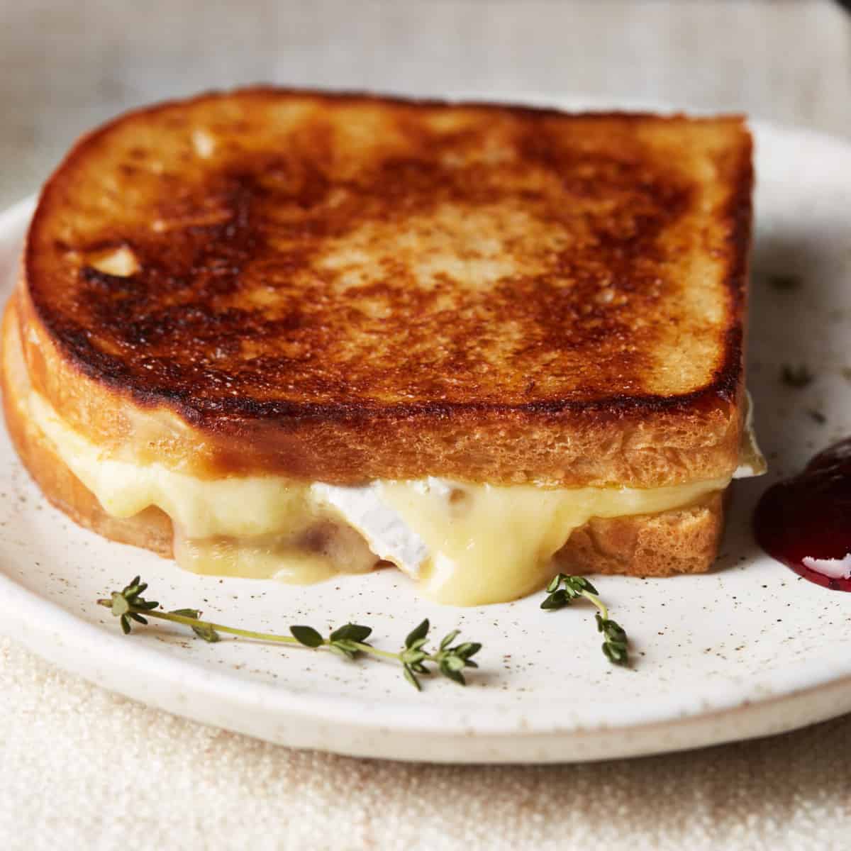 Grilled cheese on a plate with cheese coming out around the edges