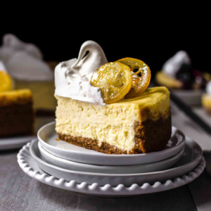 a slice of lemon cheesecake topped with meringue and candied lemons on a serving plate