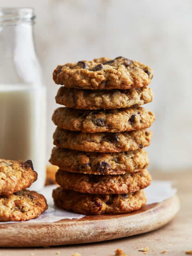 Stack of cookies on a wooden board with a jug of milk