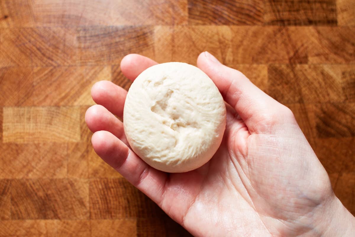 Holding a round-shaped piece of dough in a hand