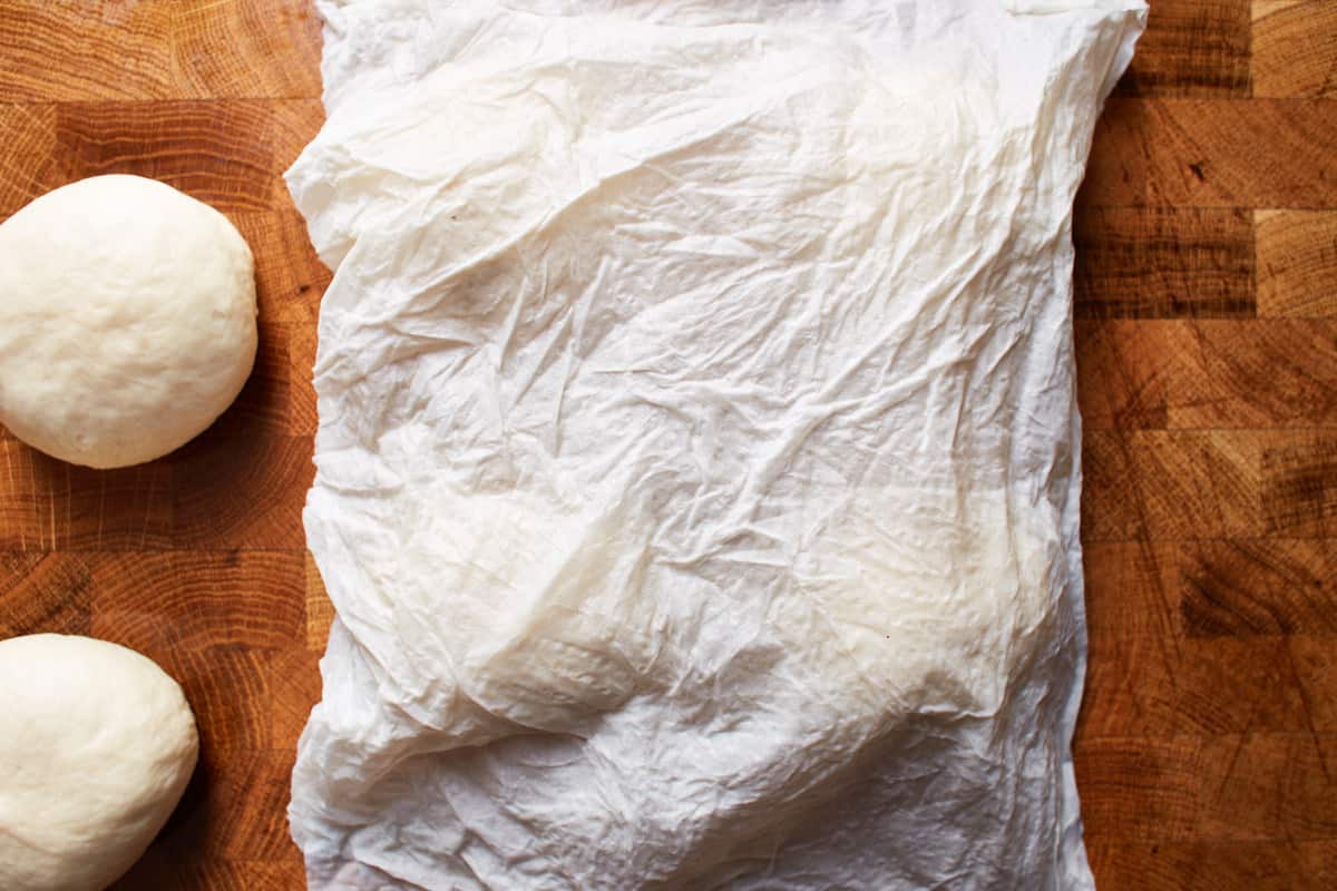 Damp paper towel covering balls of dough