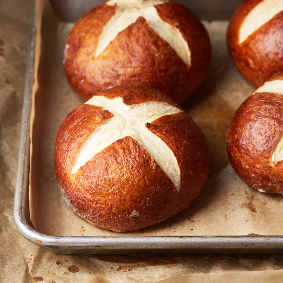 Baked pretzel buns on a baking tray with baking paper