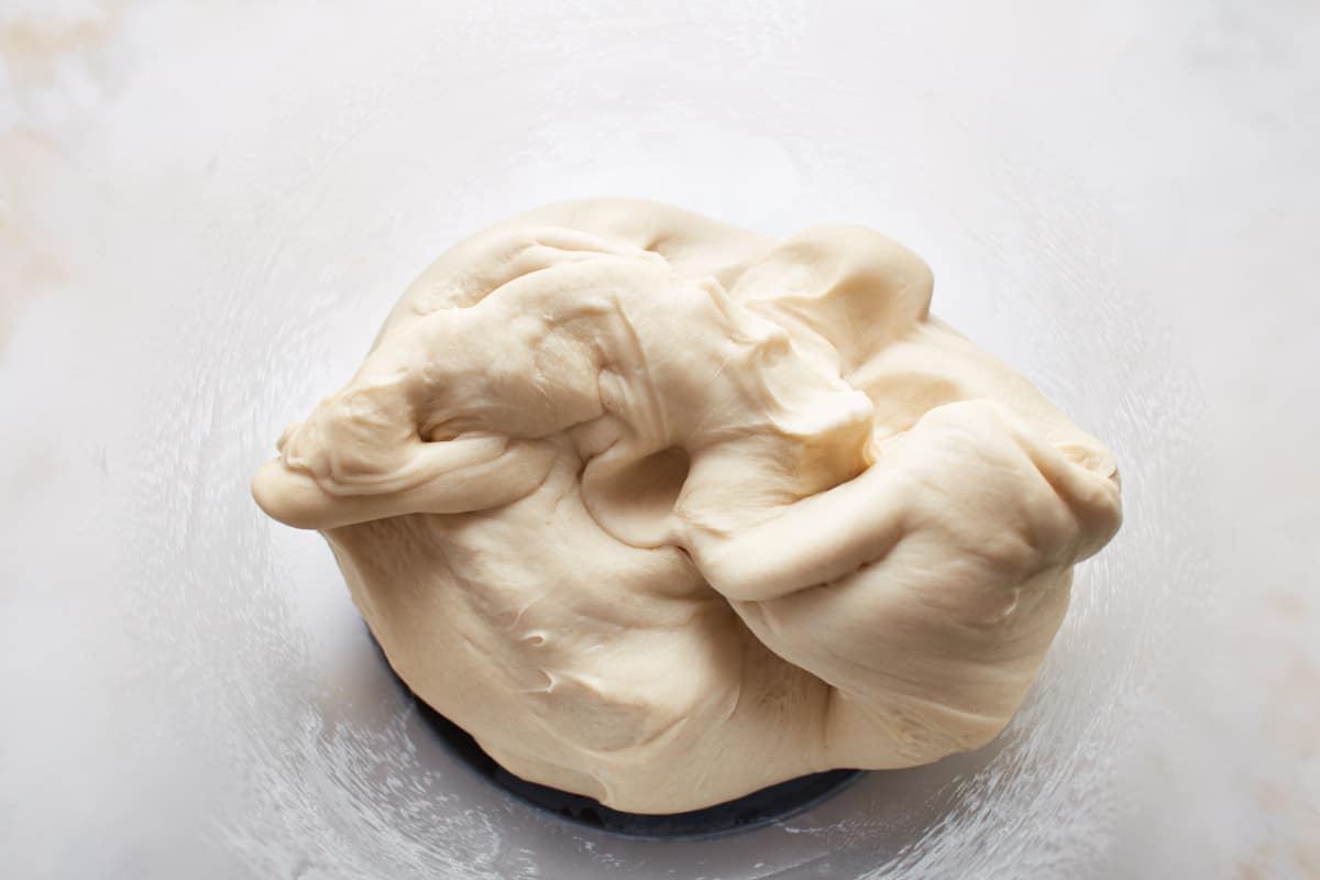 Kneaded pretzel dough in a large glass bowl