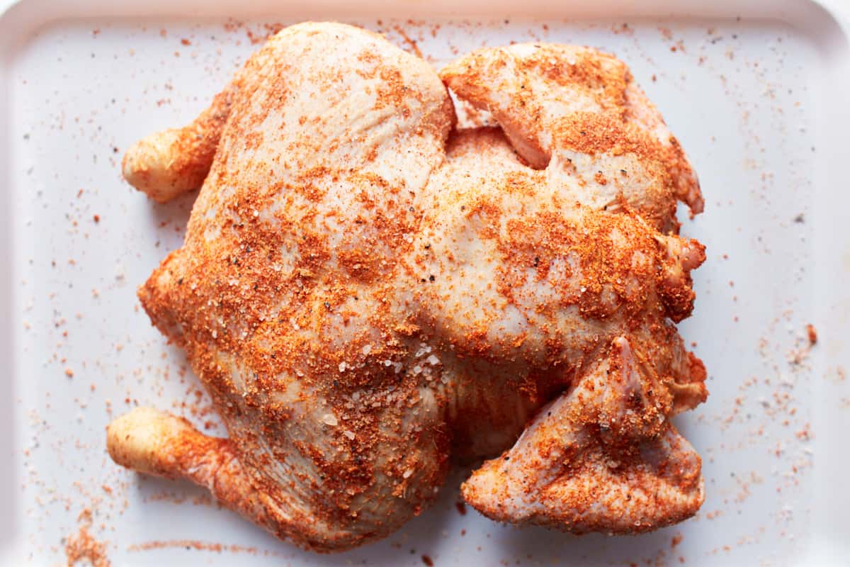 Raw chicken rubbed with spices on a white tray