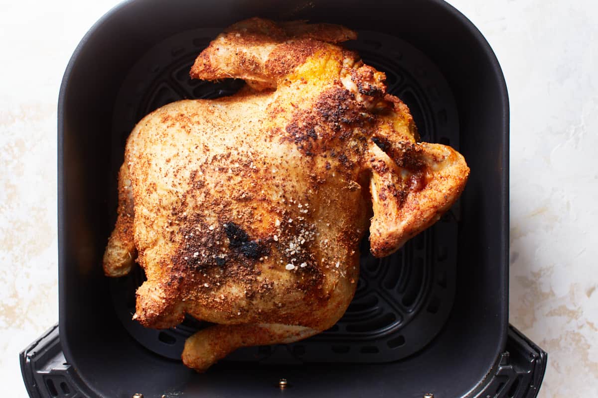 Half cooked chicken in an air fryer basket
