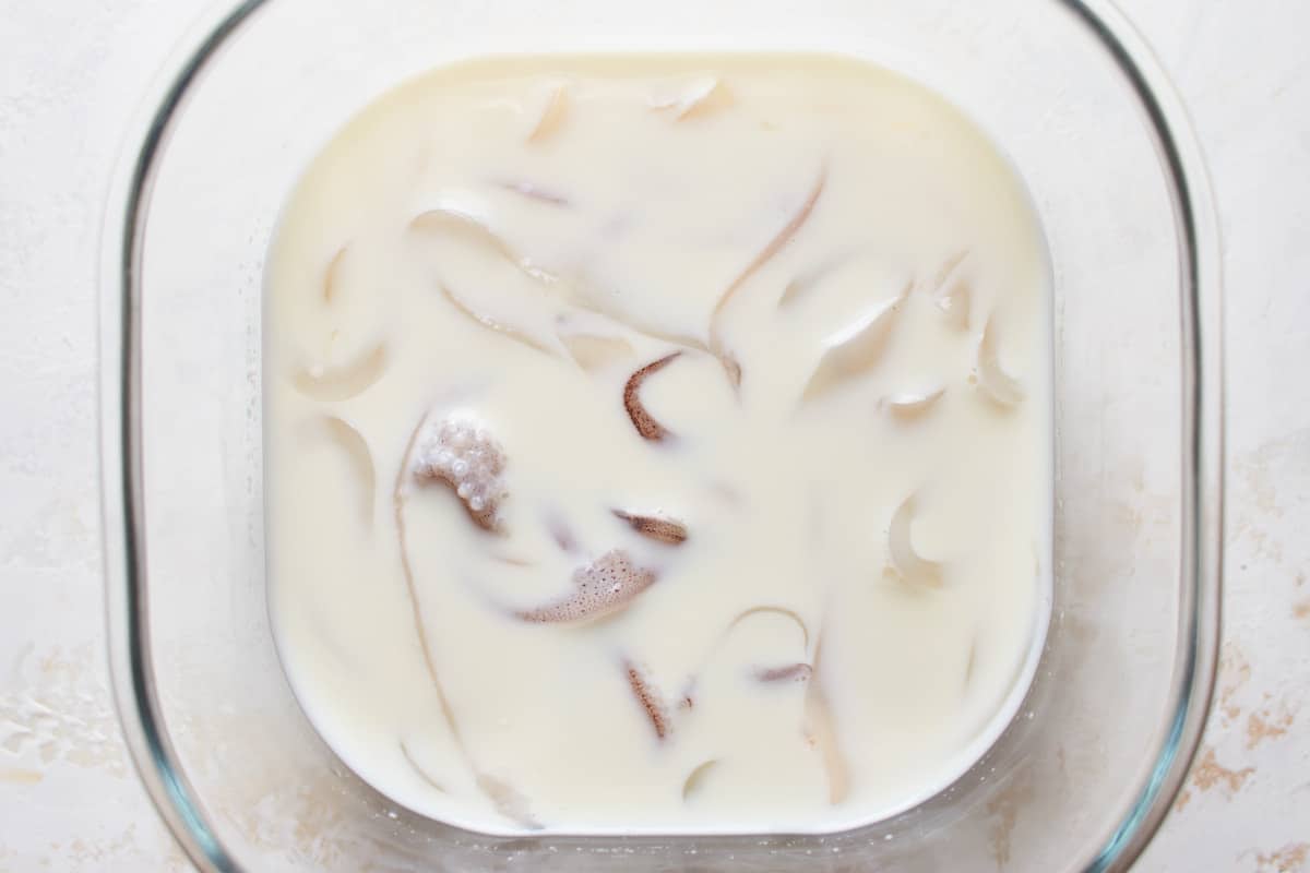 Cut squid rings and tentacles soaked in milk in a glass bowl