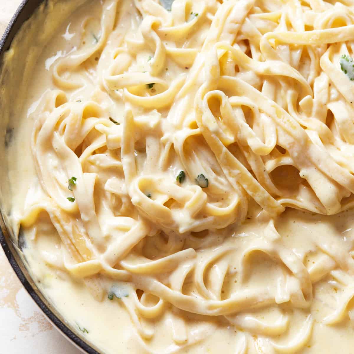 Fettuccine pasta covered in Alfredo sauce in a large pan