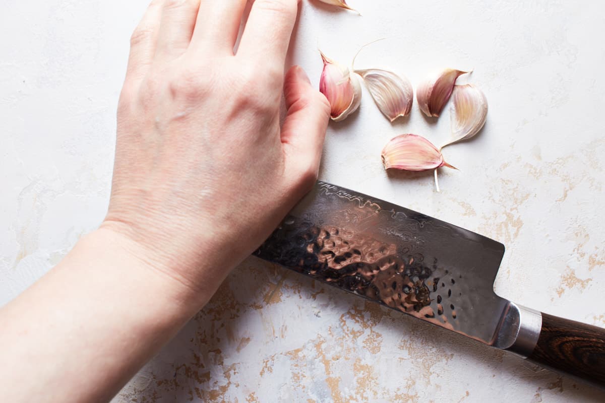 Cracking garlic clove with a large kitchen knife