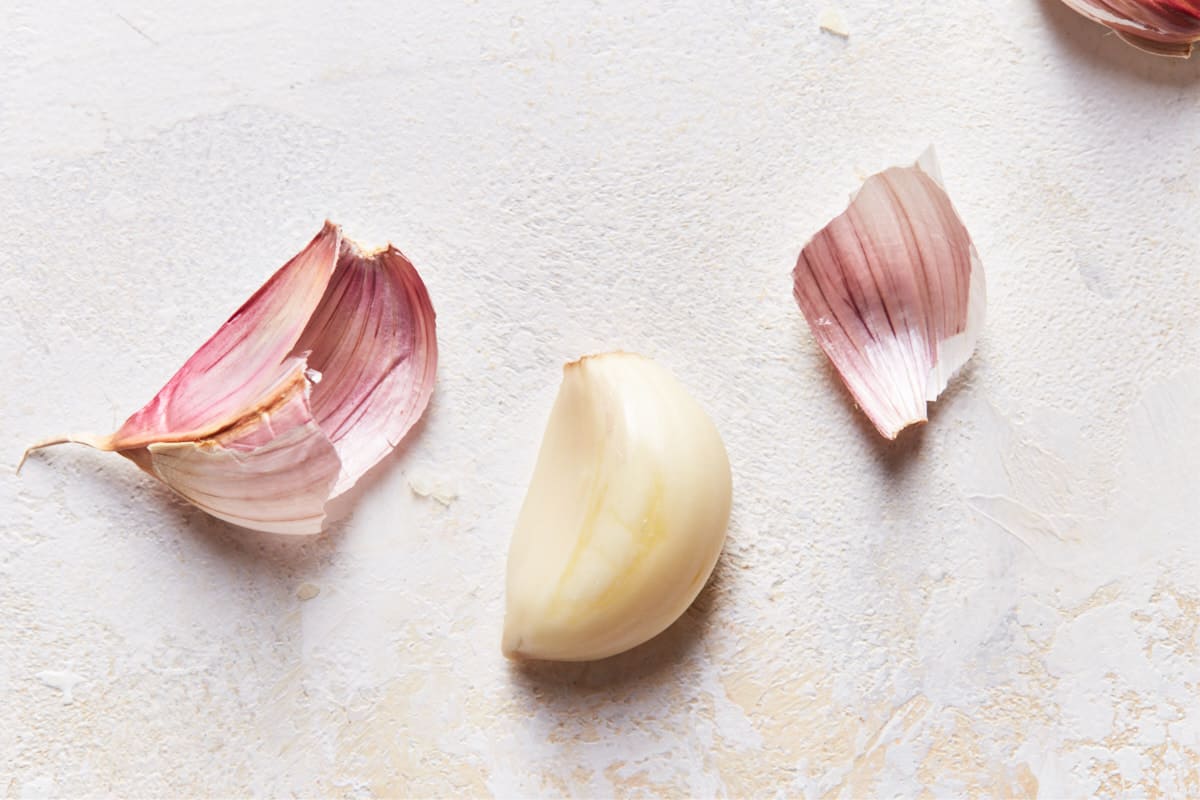 Peeled clove of garlic with the peel next to it