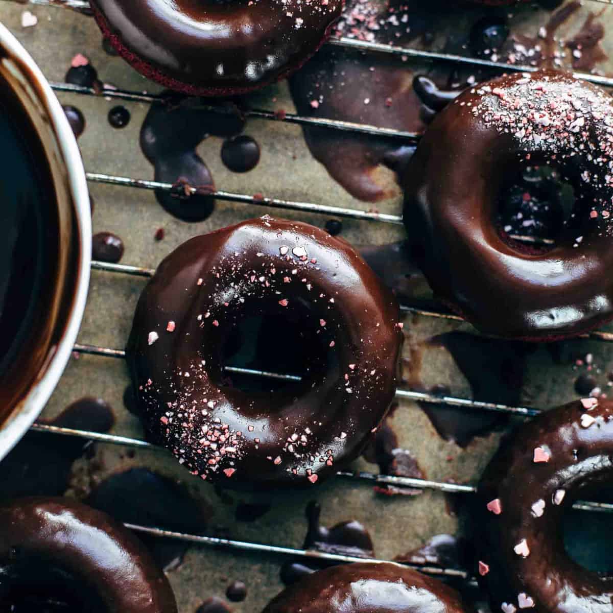 Baked red velvet cake donuts glazed with chocolate glaze on a wire rack