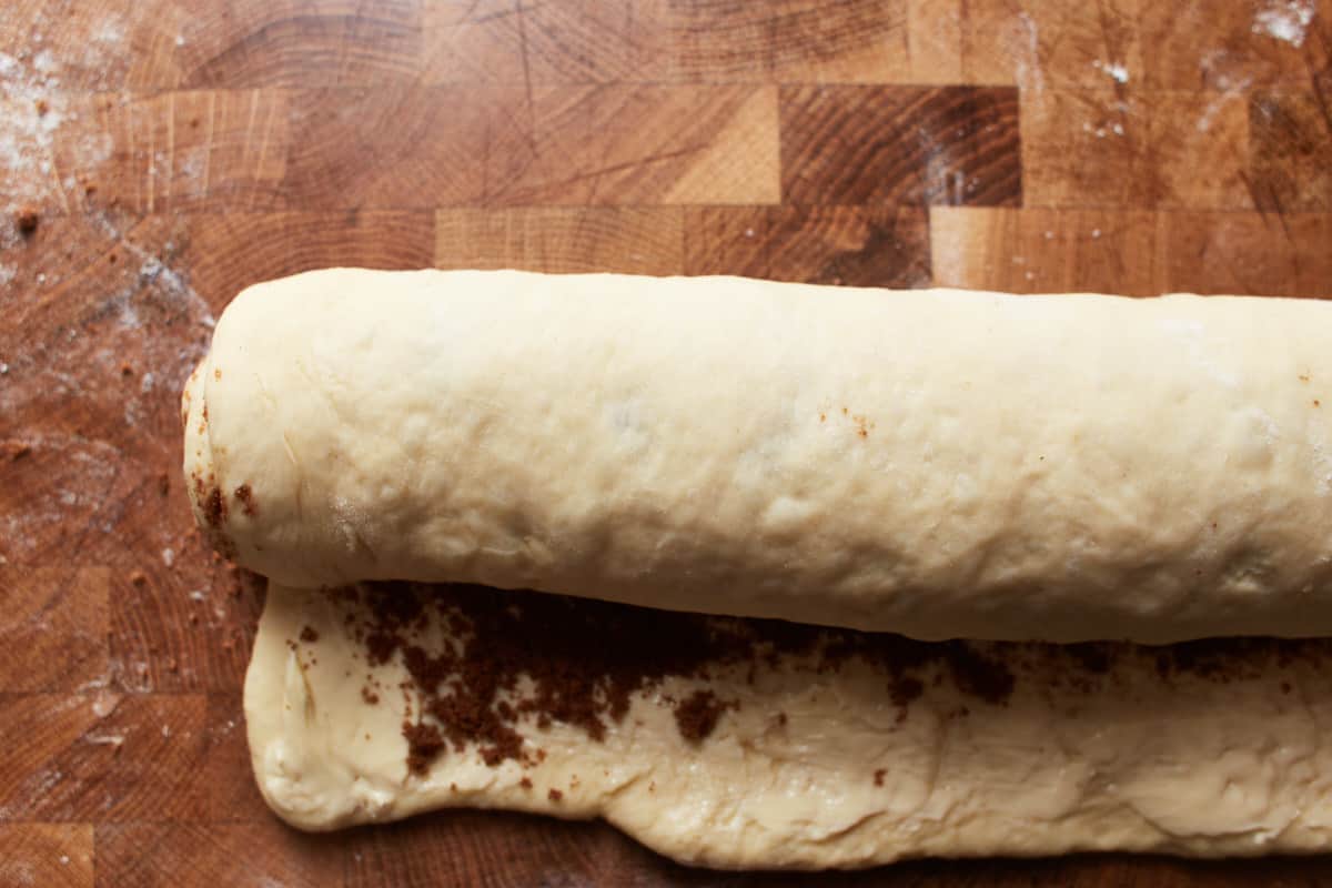 Rolling up a rolled out dough that is filled with brown sugar and butter