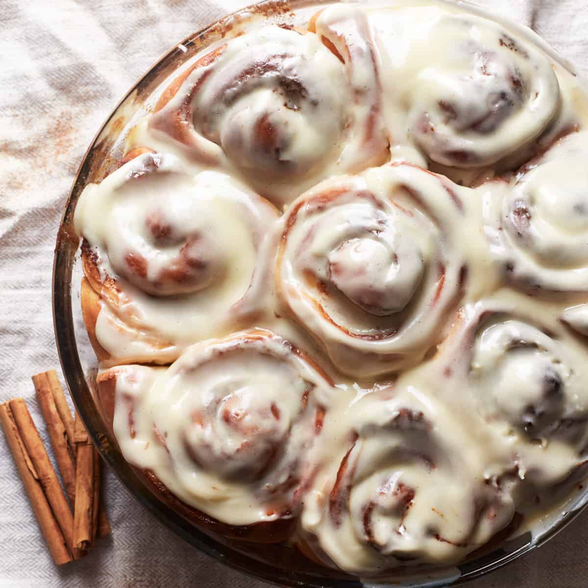 Baked and frosted cinnamon rolls in a round baking dish